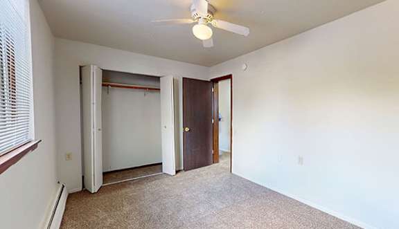A room with a ceiling fan and carpeted floor.