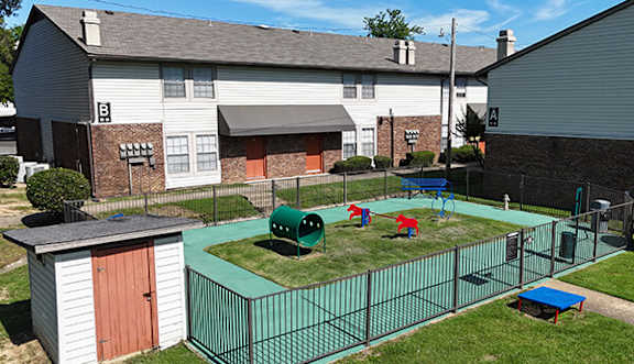 A playground with a green fence and a red slide.