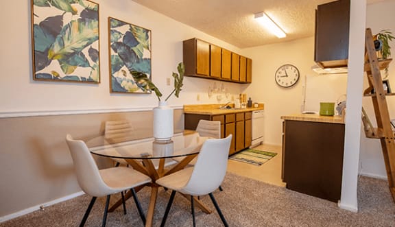 a dining area with a table and chairs and a kitchen in the background