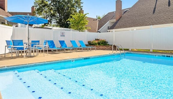 a swimming pool with blue chairs and a white fence