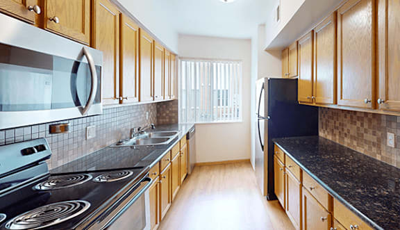 A kitchen with wooden cabinets and a black countertop.