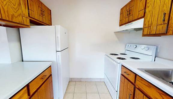 A kitchen with white appliances and wooden cabinets.