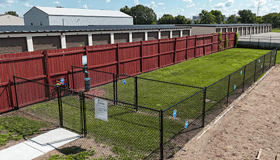 A long black fence surrounds a green field.