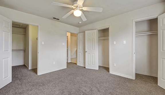A room with a ceiling fan and carpeted floor.