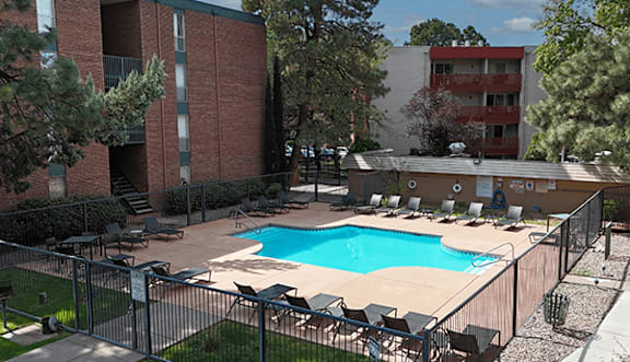 A pool surrounded by a fence and chairs.