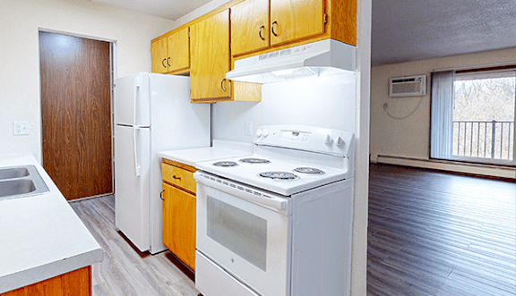 A kitchen with white appliances and wooden cabinets.