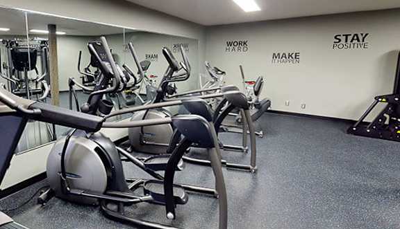 A gym with a row of treadmilers and a wall that says "Stay Positive".