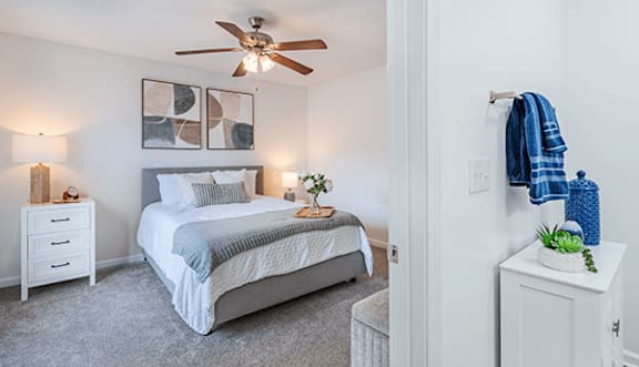 A bedroom with a bed, nightstand, and a ceiling fan.
