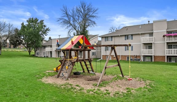 a swing set in a yard with an apartment building in the background