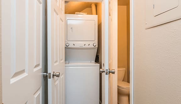 A white door is open to a small bathroom with a toilet and a white cabinet.