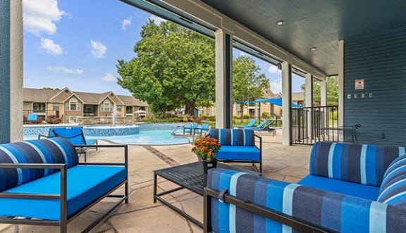 a pool with blue chairs and a poolside patio