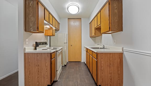 a kitchen with wood cabinets and white appliances and a door to a refrigerator