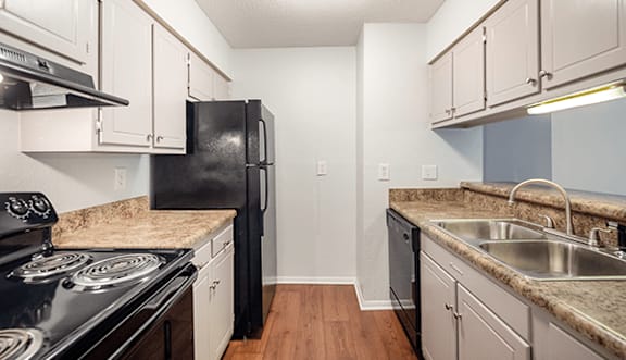 A kitchen with black appliances and white cabinets.