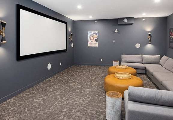 a living room with couches and a screen on the wall