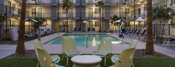 A pool surrounded by chairs and tables in a courtyard.