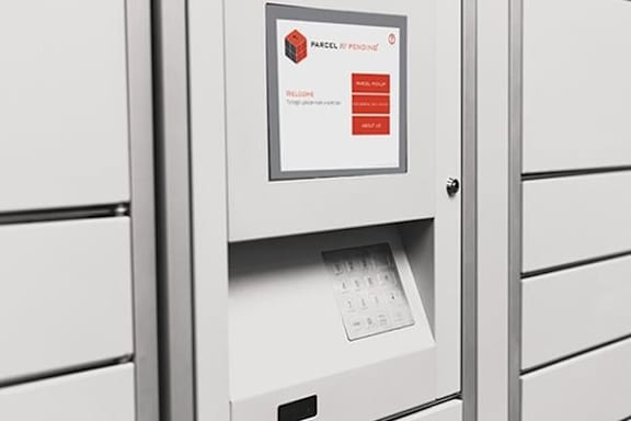 A white van is parked on the street with a man in a blue shirt and a man in a grey shirt standing next to it.