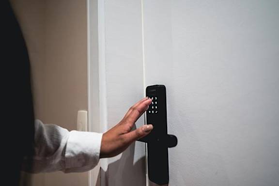 A person is pressing a button on a black door handle.