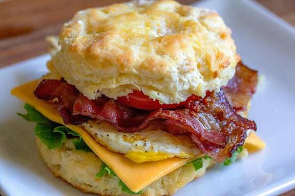 A breakfast sandwich with bacon, egg, and cheese on a biscuit.