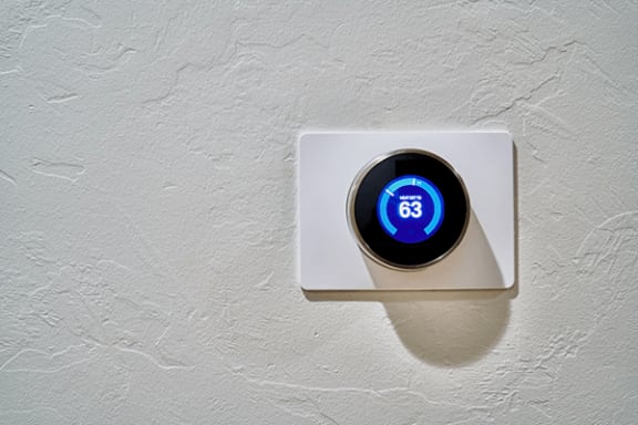 an electric thermostat sitting on a white wall