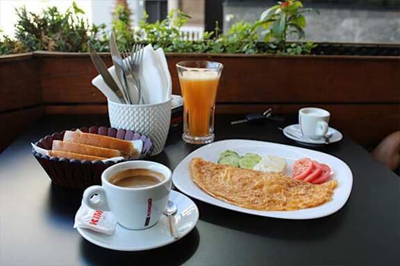 A breakfast table with coffee, orange juice, bread, and an omelet.