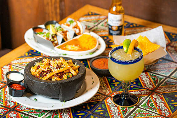 A table with a bowl of nachos and a margarita glass.