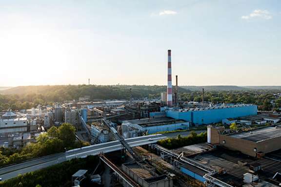 A large industrial area with a tall chimney and a blue building.
