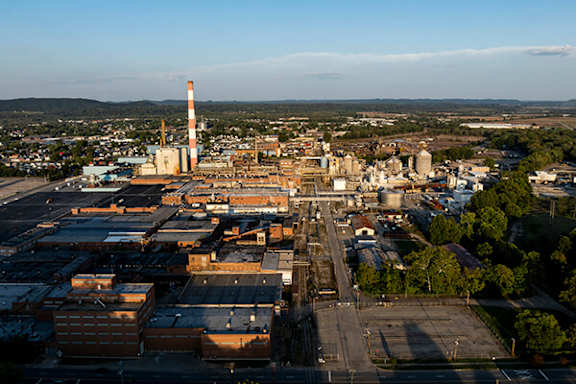 A large industrial area with a tall chimney is seen from an aerial perspective.