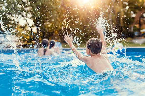 A person is swimming in a pool with water splashing around.