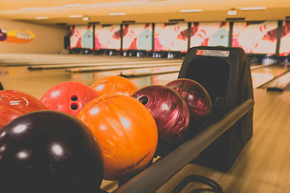A bowling ball is placed on a rack in a bowling alley.