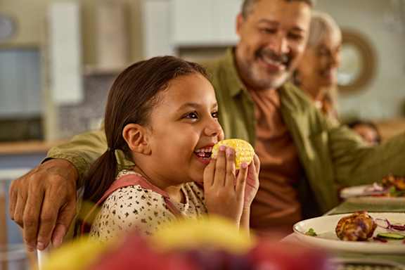 A girl eating a lemon while sitting with her family.