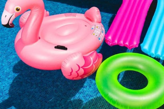 a pink inflatable flamingo toy on a blue