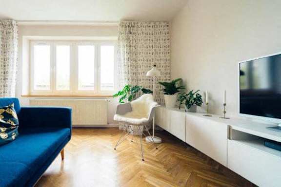 A living room with a blue sofa, a white chair, and a television.