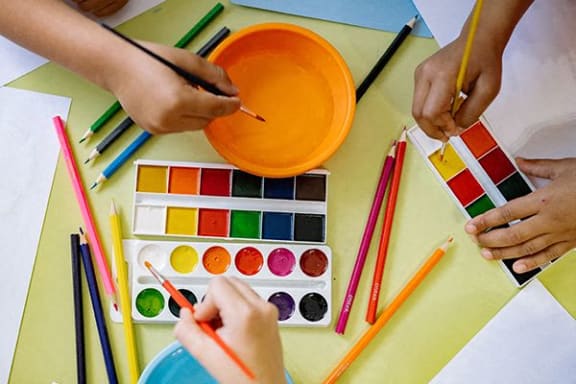 a group of people painting a bowl with colored pencils