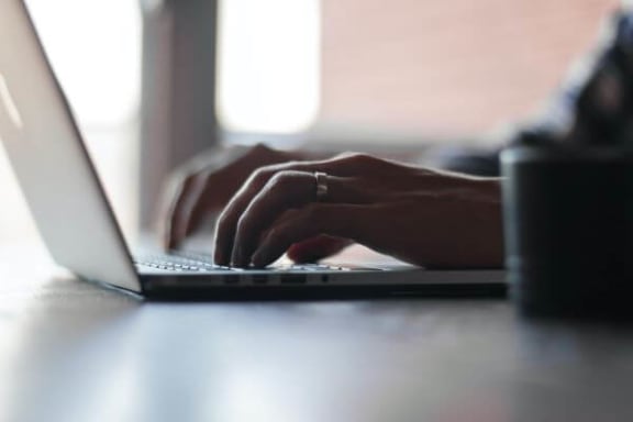 a person is typing on a laptop computer