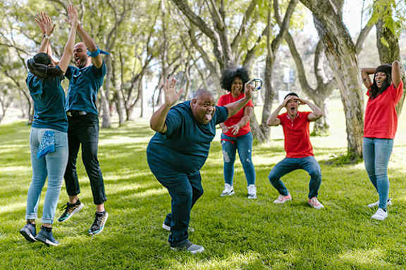 A group of people are dancing in a park.
