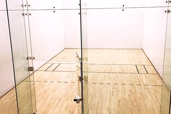 A squash court with a net and wooden floor.