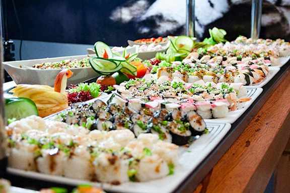 A variety of sushi dishes are displayed on a wooden table.