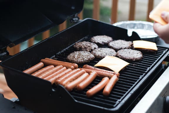 a grill with hot dogs and hamburgers on it