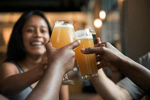 Two people toasting with beer glasses in a bar.