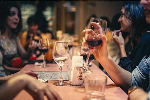a group of people sitting around a table drinking wine