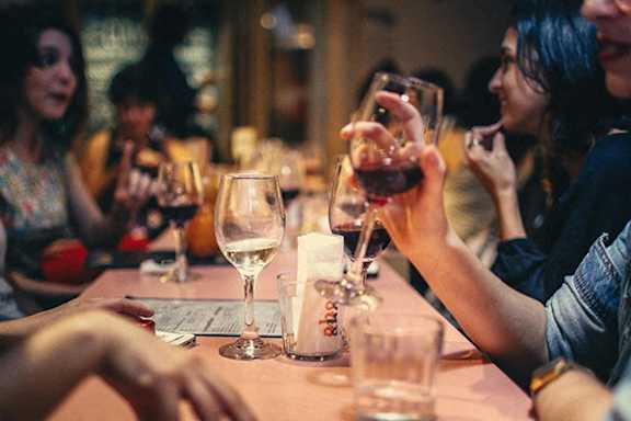 A group of people are sitting around a table enjoying a glass of wine.