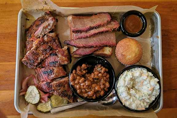 A tray of food including beans, coleslaw, and cornbread.