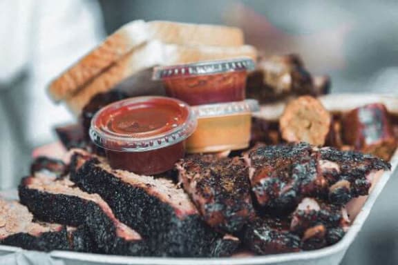 a plate of food with barbecue and dipping sauces