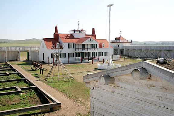 A white building with a red roof is surrounded by a wooden fence.
