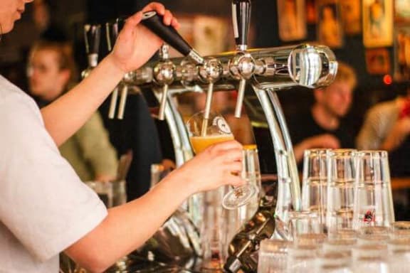 a person pouring a glass of beer in a bar