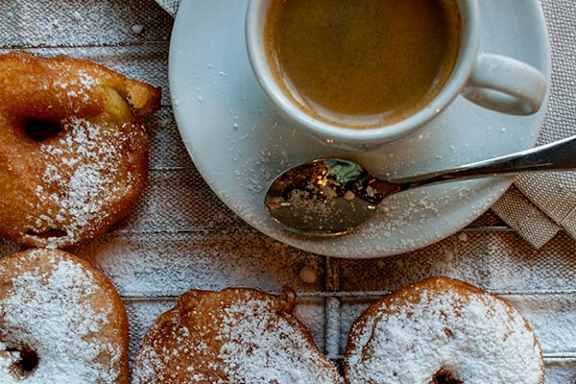 Donuts with powdered sugar and a cup of coffee.