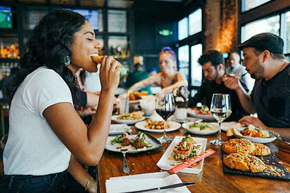 A woman is eating in a restaurant with a group of people.