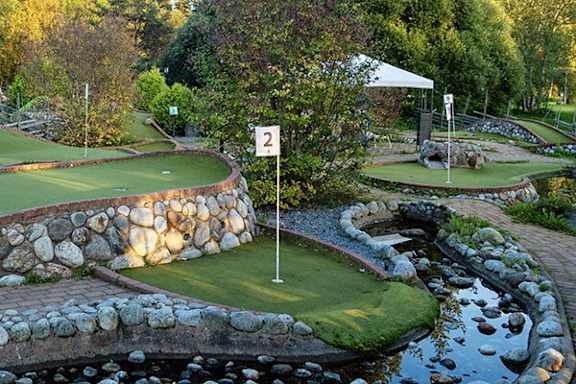 A golf course with a water feature and a white tent.