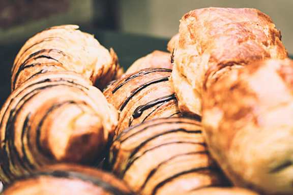 A close up of a variety of baked goods, including a loaf of bread and some pastries with a golden-brown crust.