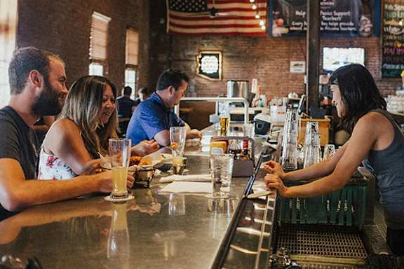 A woman is serving a customer at a bar.
